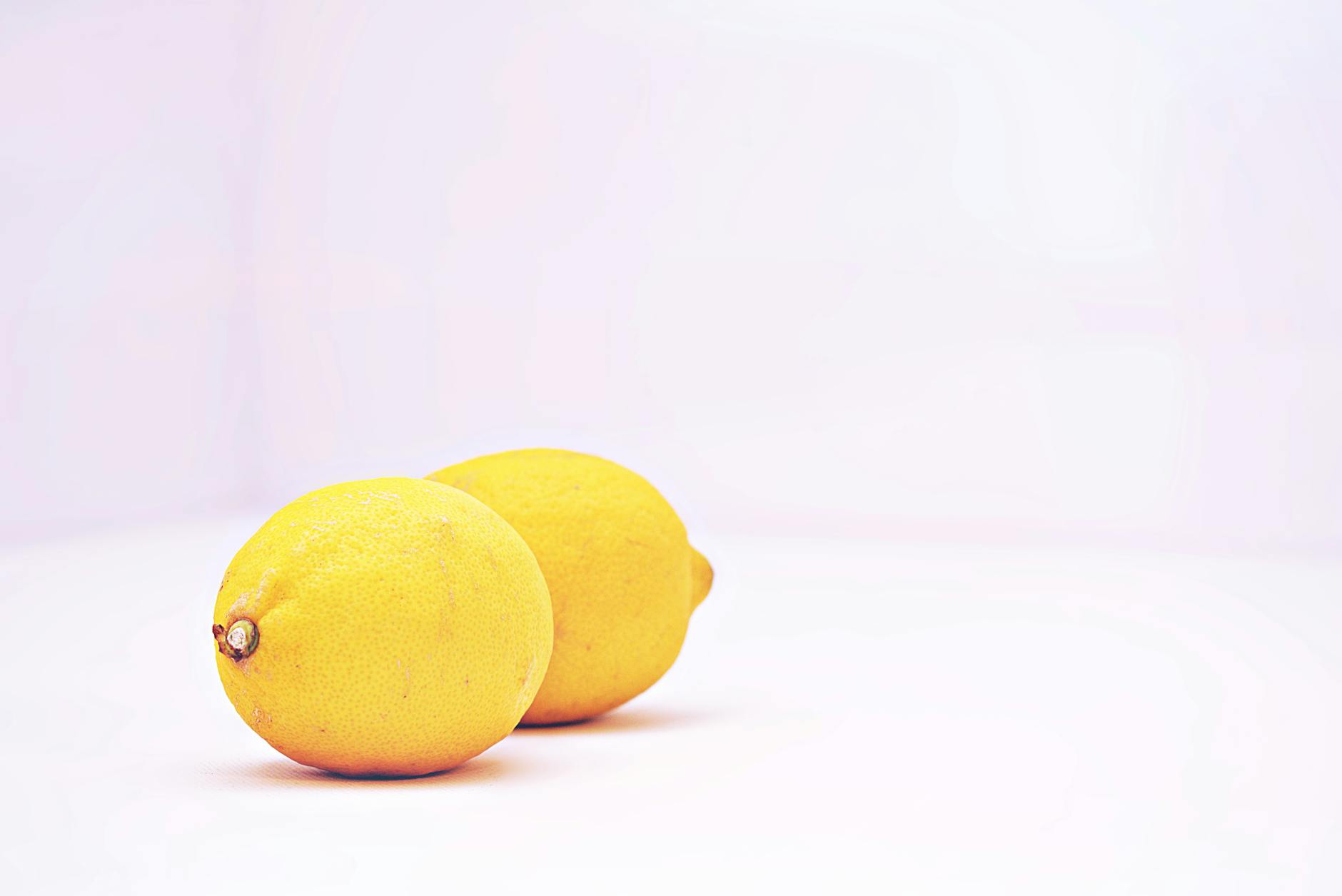 Two vibrant lemons against a white background, symbolizing fresh pleasure and connection