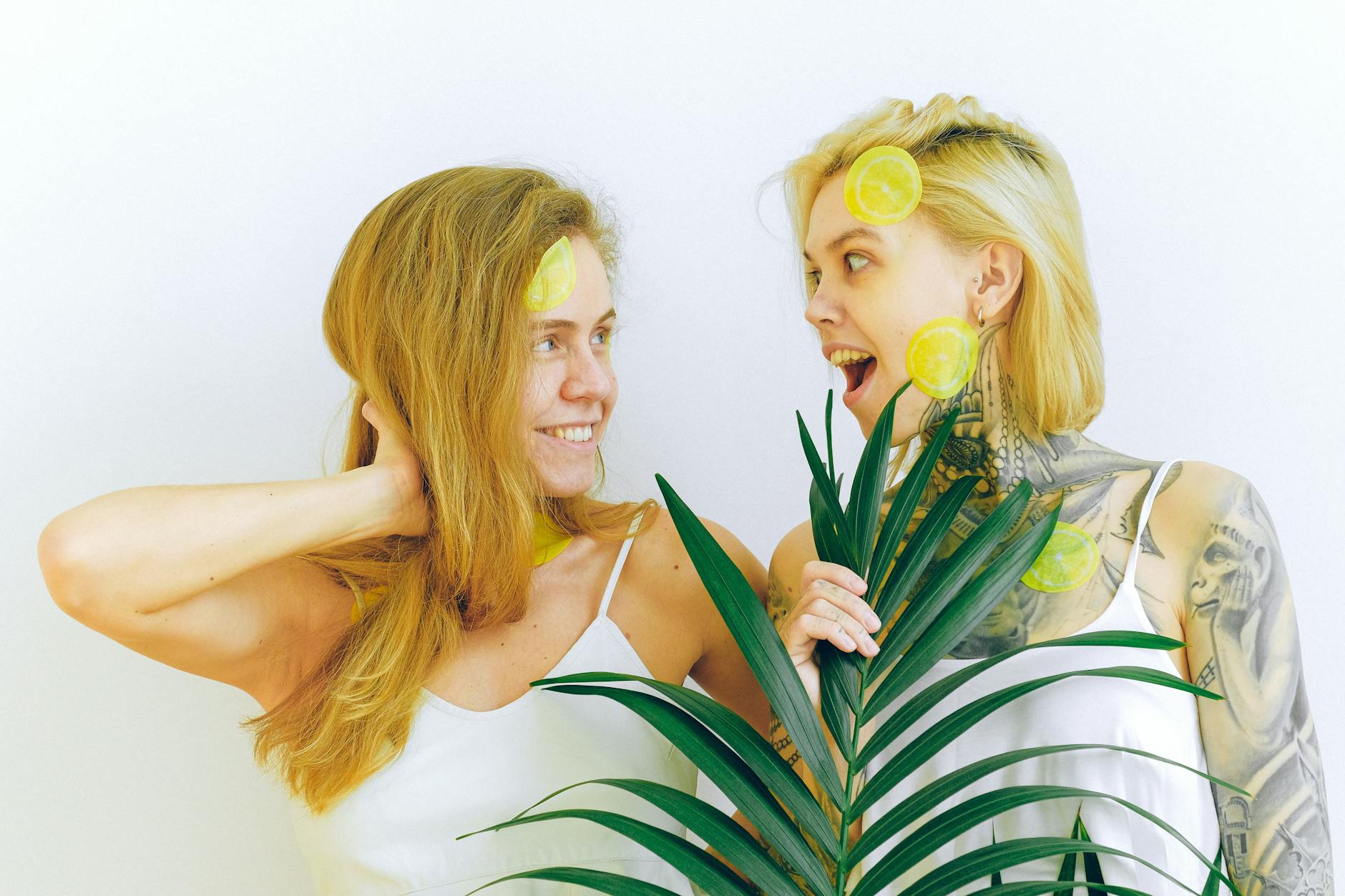Two women smiling together with lemon slices, representing joy and openness in intimate relationships