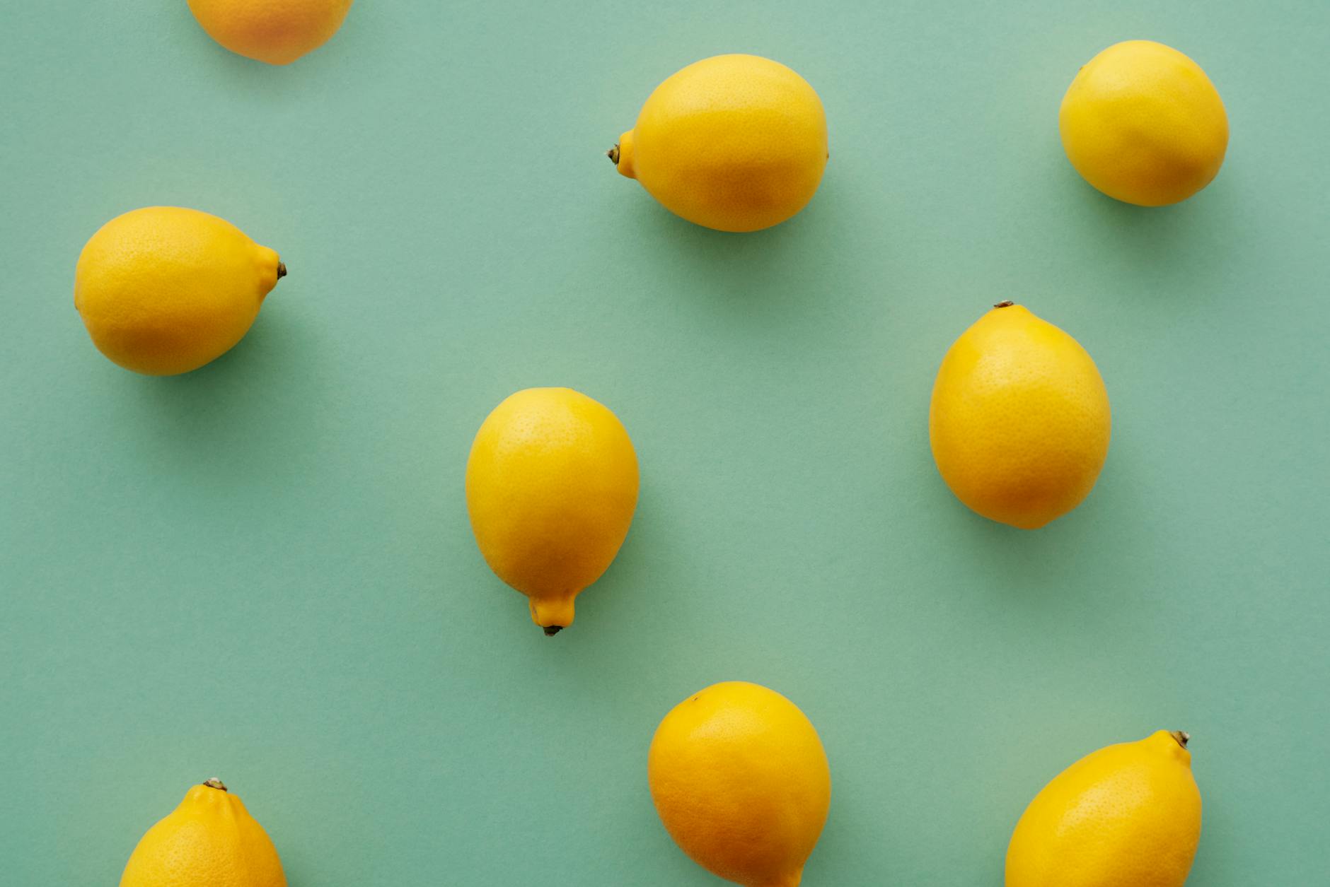 Bright yellow lemons arranged on a pastel green background, representing the Helo Nancy lemon vibrator design.