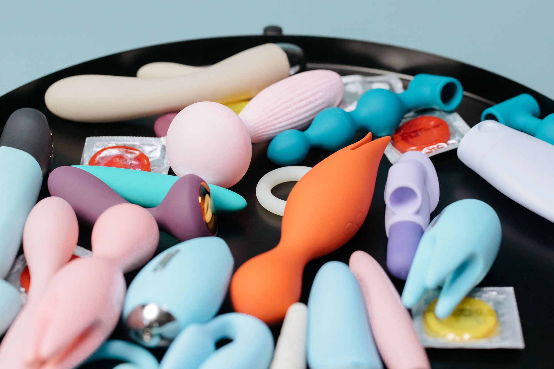 A collection of silicone vibrators in various colors and textures arranged on a dark surface