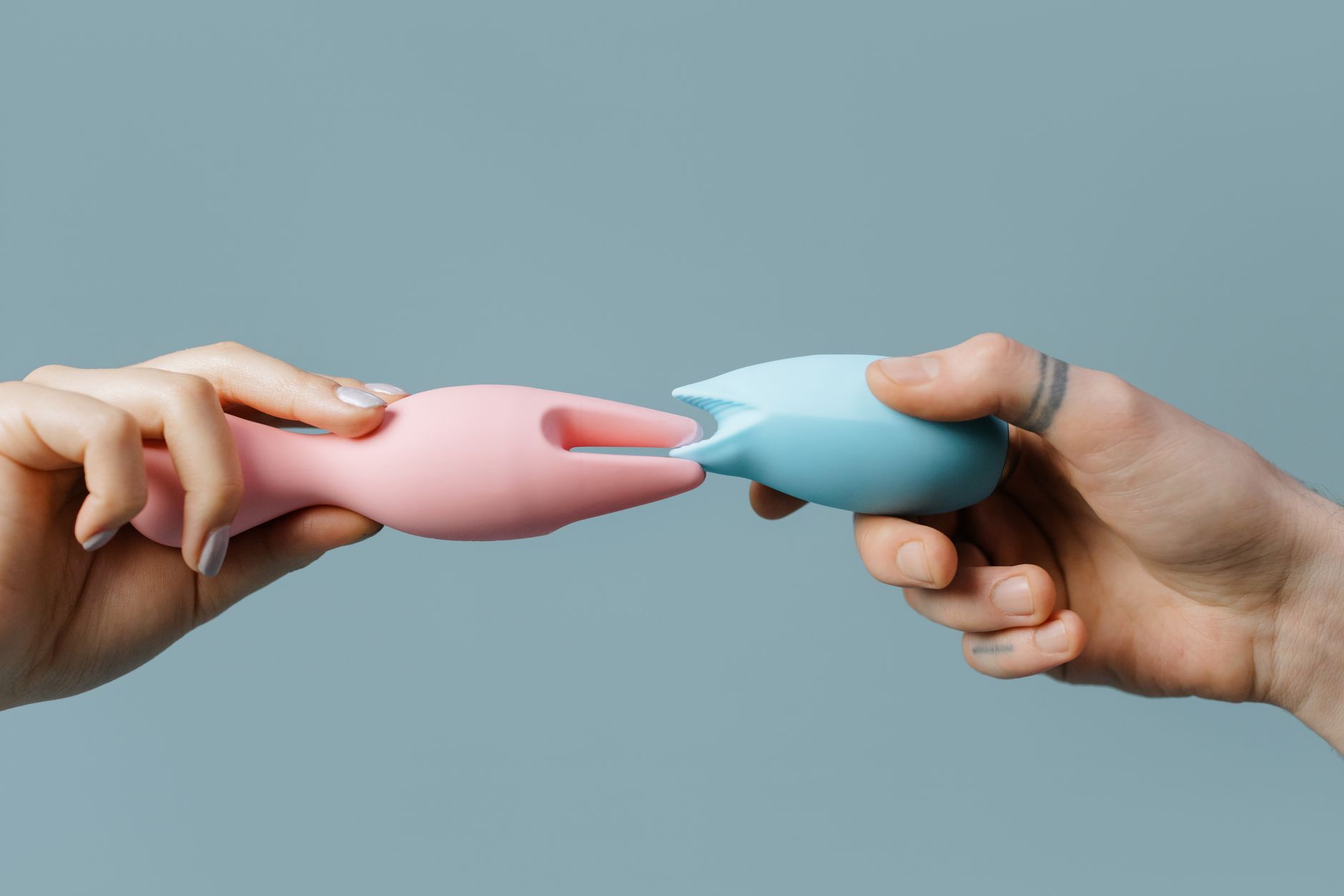 Woman holding two colorful clitoral vibrators, one of which is a lemon-shaped suction toy