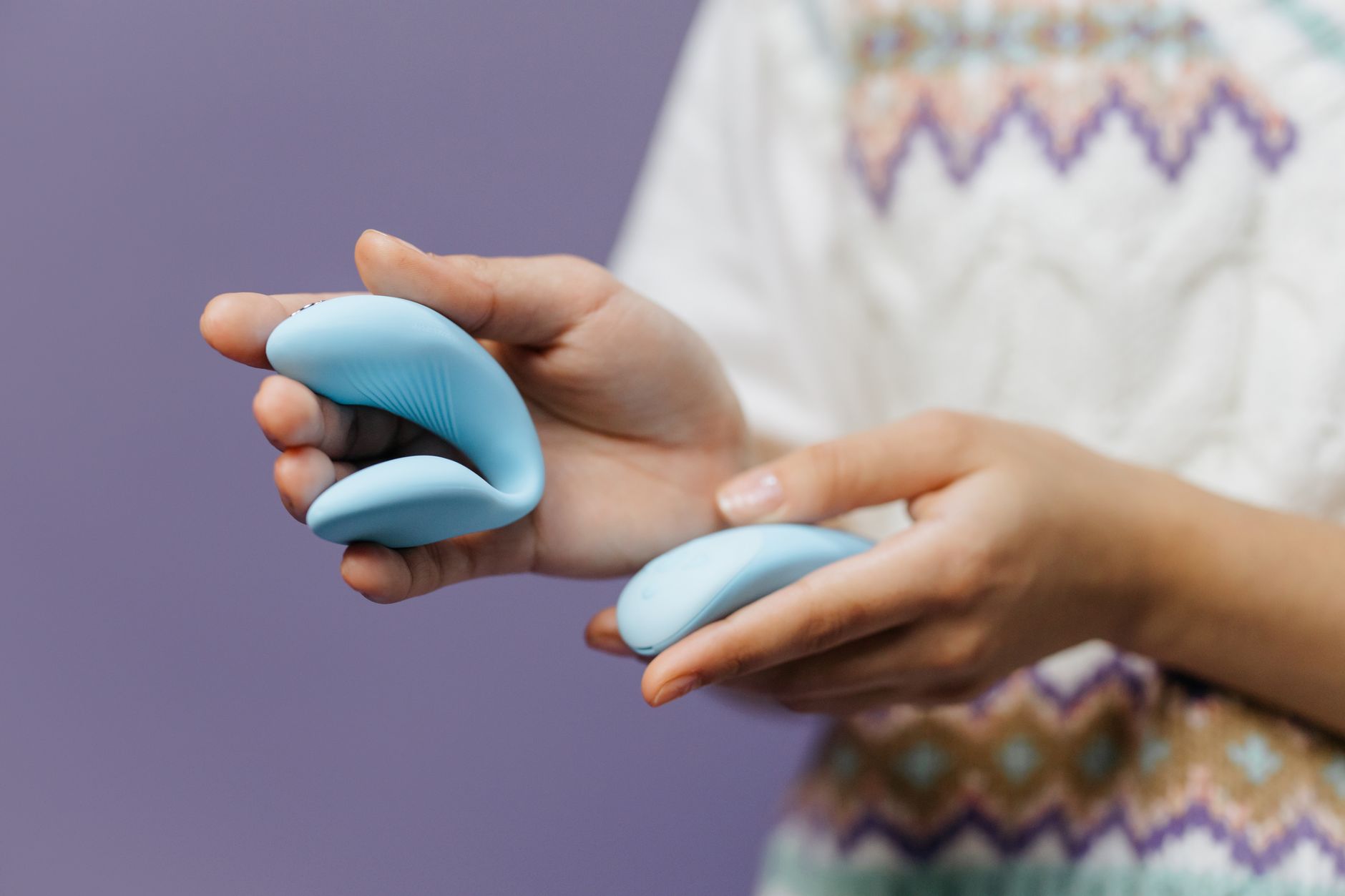 Two hands holding a sleek lemon-colored vibrator together, representing shared intimacy and reconnection.