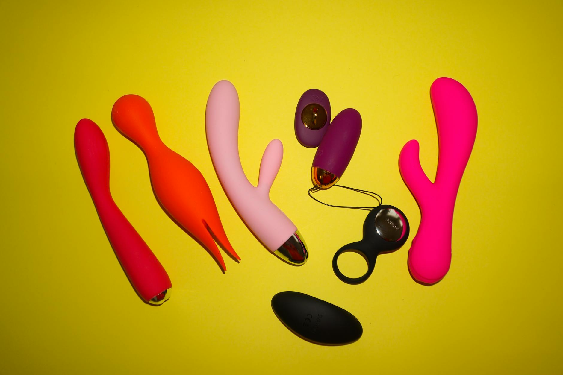 Hands holding pastel-colored silicone vibrators for intimate pleasure